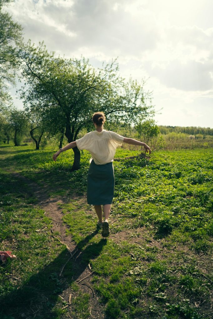 Femme marchant dans la nature les bras ouverts, évocation de l’équilibre, de la vitalité et du bien-être